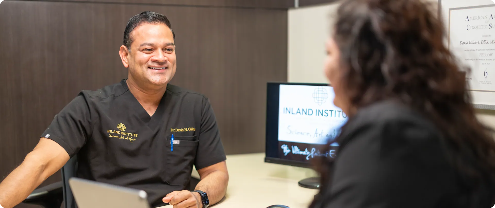 Dr. David H. Gilbert smiling during a consultation with a patient