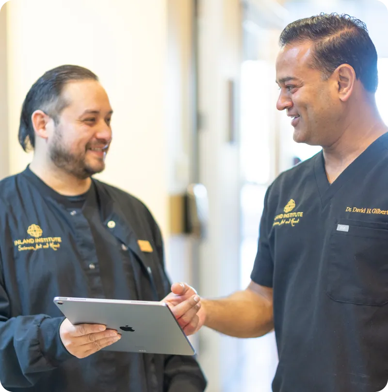 Dr. David H. Gilbert talking with a colleague holding a tablet
